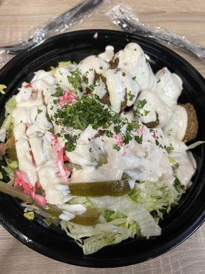 Falafel bowl. Pickled vegetables,yellow rice, lettuce, tomatoes covered in house made tahini ranch sauce and topped with fresh parsley.