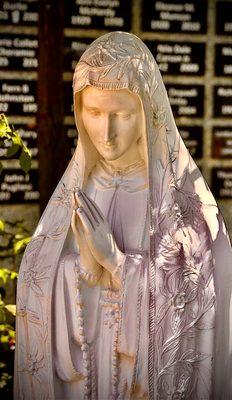 Virgin Mary statue in front of the memorial wall.