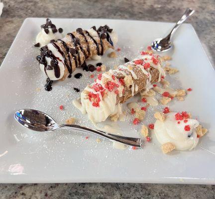 Two types of cannolis: one is chocolate with chocolate chips and a chocolate drizzle / one is strawberry bites and cannoli cream