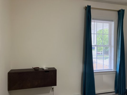 antique desk, wall mounted 
 curtain rods & curtains hung.