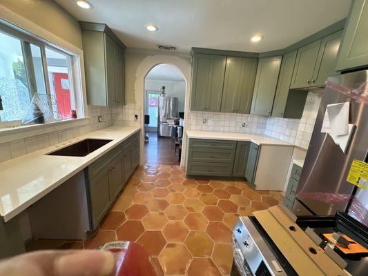 Spanish remodel kitchen with green cabinets and Saltillo tile flooring