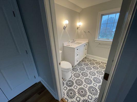 White Bathroom vanity with patterned floor tiles.