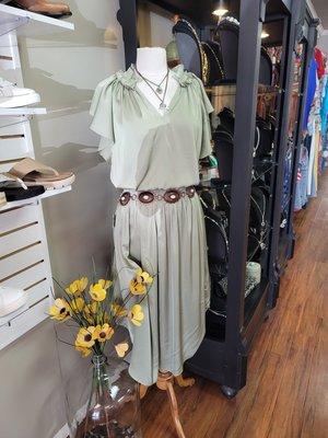 Green dress accessorized with belt on a mannequin