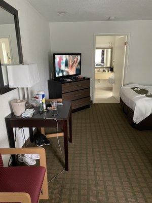 One side of hotel room tv dining table two chairs on the side of table