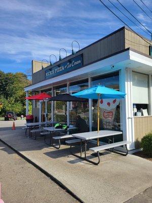 The out side of Nick's Pizza and Ice Cream. There is outdoor seating.