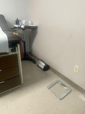 Corner of exam table has exposed foam from inside. UV lamp stored on the floor.