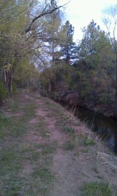 Walking path next to irrigation channel, behind park.