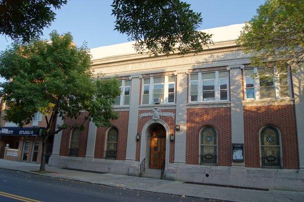 The synagogue’s two-story tall, five-bay wide façade, in brick with cast-stone trim, is defined by double-height Ionic piers