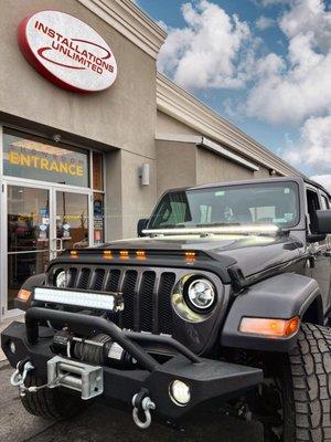 Jeep JL w/AVS LightShield, Metra 7" LED Headlight/Fog Light Combo, Rough Country 20" Dual Row LED Light Bar & 50" LED Windshield Kit.