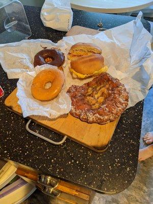 Breakfast sandwich, apple fritter, glazed donut, and chocolate glazed donut.