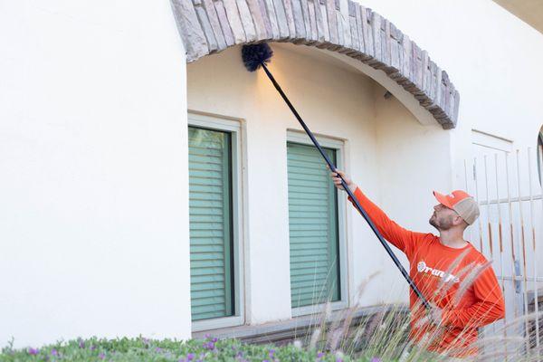 Orange Technician Dewebbing around windows