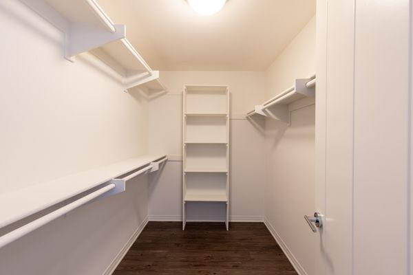 Large walk in closet with floor to ceiling hardwood clothing storage and racks.