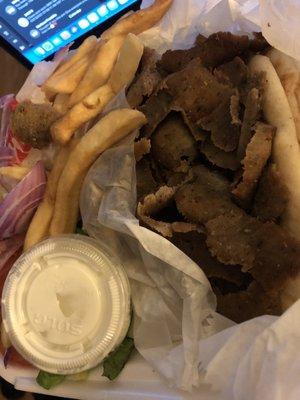 Dried out overcooked gyros meat on plate with two pitas, fries and salad.