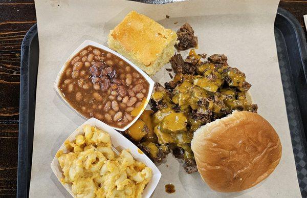 Smoked brisket sandwich with cornbread, baked beans, and mac N cheese