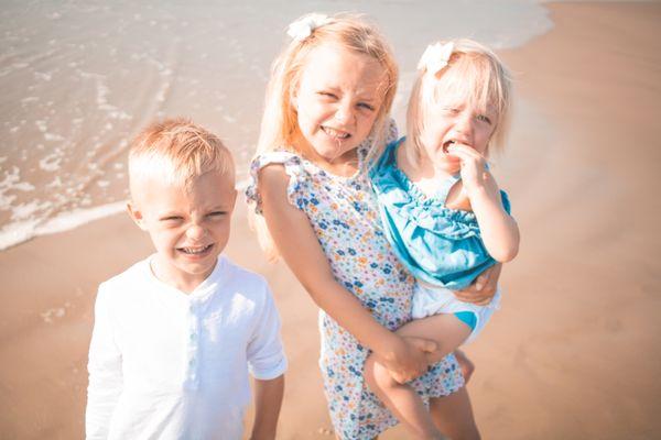 Children smiling for a photo on the beach with cinematic edits.