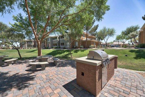 a brick patio with a grill and picnic tables at Desert Sage