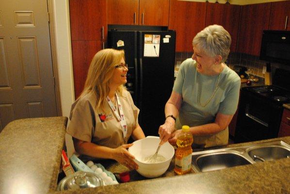 Caring Senior Service caregiver helping a client make dessert