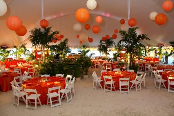 Tent event on the beach with foliage, paper lanterns, custom linens and centerpieces.