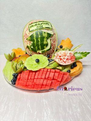 Carved watermelon with a graduation hat and a diploma with a fruit arrangement for the graduation party