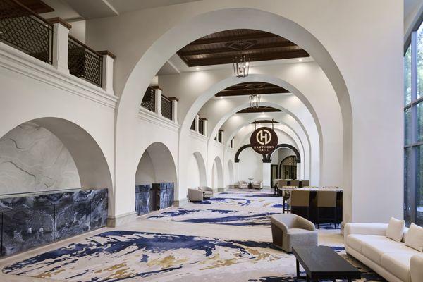 Elegant lobby hallway featuring graceful arches and floor-to-ceiling windows, offering stunning views of the lush resort grounds.