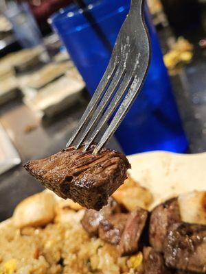 A close-up of a piece of the Filet Mignon medium rare on a fork.