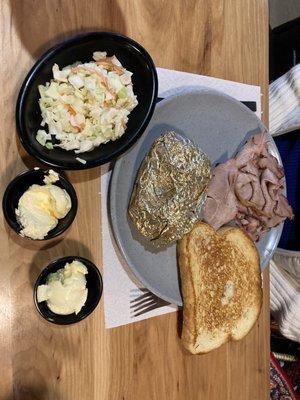 Sliced pork  baked sweet potato coleslaw and garlic bread