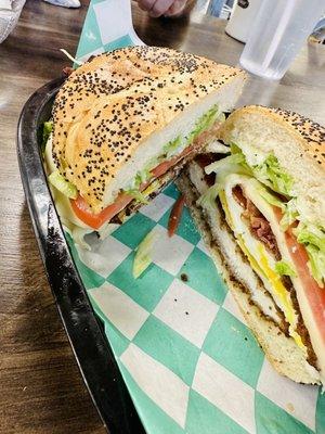 A delicious chicken cutlet breakfast sandwich with bacon, egg, lettuce, tomato on a hard roll.