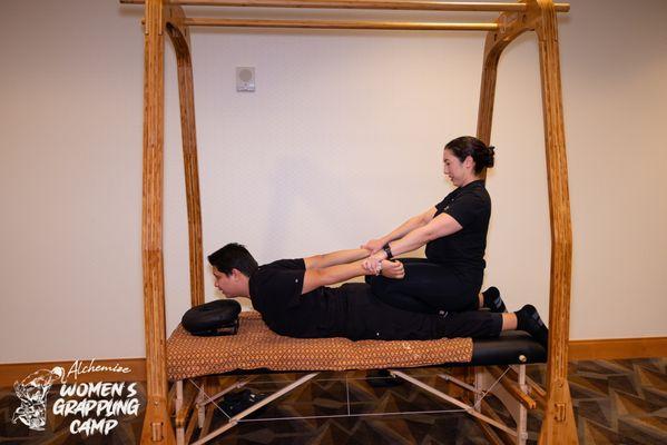 Demonstrating assisted stretching and Thai acupressure at the Alchemize Women's Grappling Camp