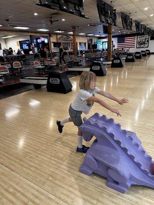 My grandson pushing his ball toward the pins.