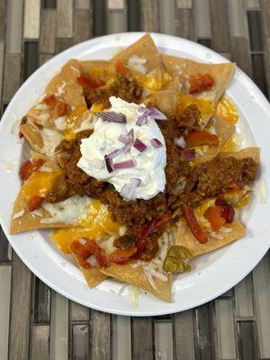 Chili cheese nachos with cherry peppers, onions and sour cream.