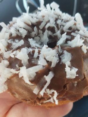 White cake donut, chocolate frosting with a sprinkle of fresh coconut.