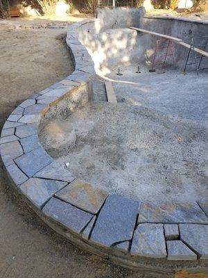 Natural stone pool coping being installed