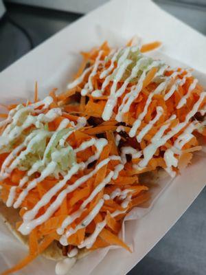 Coop Tacos. Crispy Chicken bites tossed in Buffalo sauce topped with shredded carrots, shredded celery, and ranch drizzle.