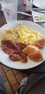 Scrambled eggs with bacon and croissant.