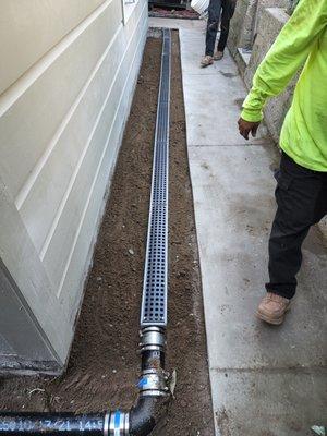 Installation of a channel drain for storm water collection at the rear of the home.