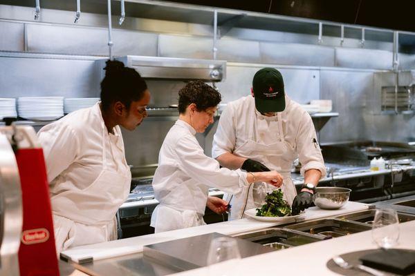 Chefs assisting each other on a dish.