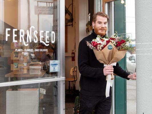 Shopper leaving Fernseed with a wrapped bouquet