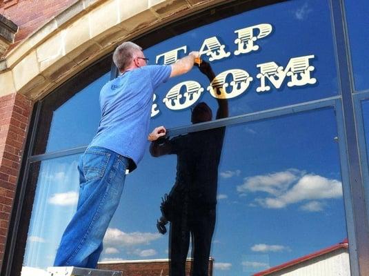 Putting the finishing touches on the Tap Room sign on the front of the Bank