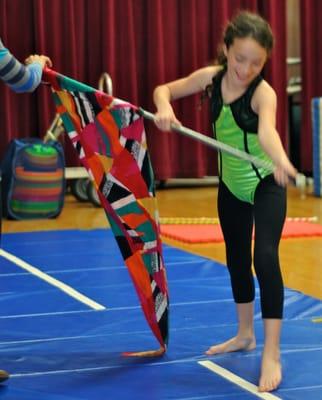 A girl learning to do cartwheels with a flag