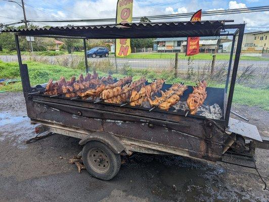 Chicken cooking over a wood fire.