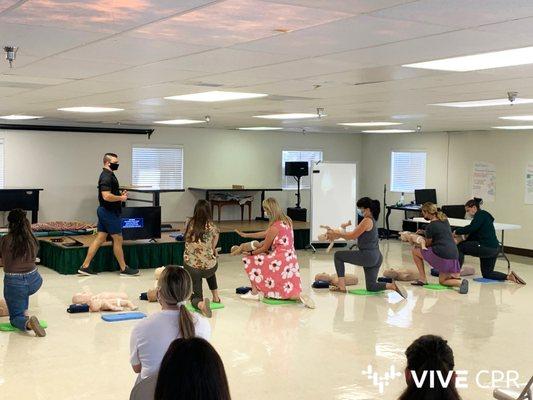 Students practice choking treatment on an infant during a CPR and First Aid class.