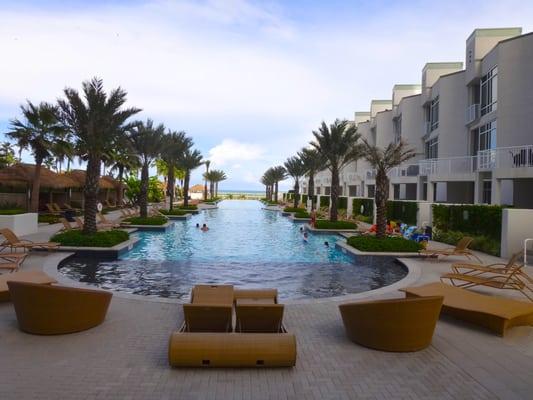 The pool is enormous with relaxing outdoor furniture.