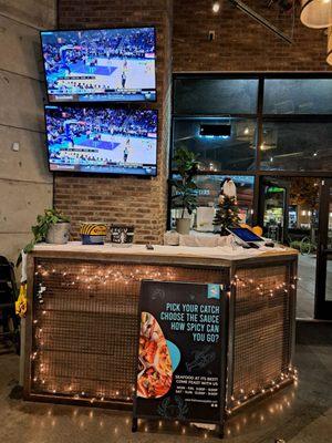 Inside restaurant - Hostess Stand - 2 large screen TVs set to NBA game