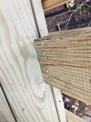 Railing post secured with an abundance of framing nails. Does not meet building code.