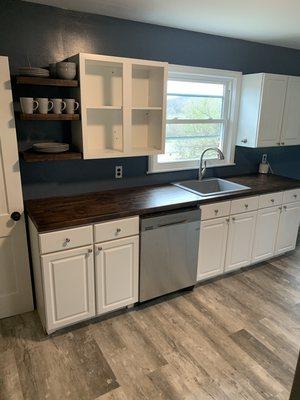 Kitchen after remodel with custom floating shelves made from leftover custom butcher block counter tops. EVP flooring and granite sink