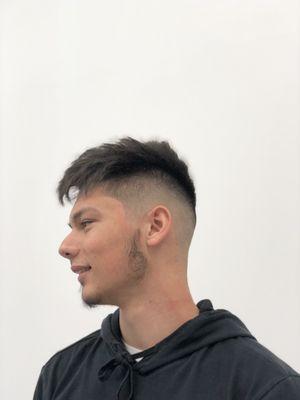 A skin fade with a textured scissor hair cut on top.