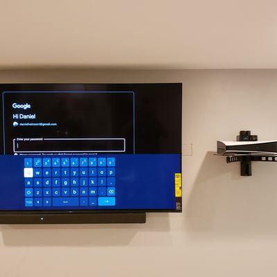 Mounted UiltraSlim Sony UHD tv with PS5 on a shelf