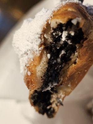 Close-up of a black plastic fork holding a fried Oreo.