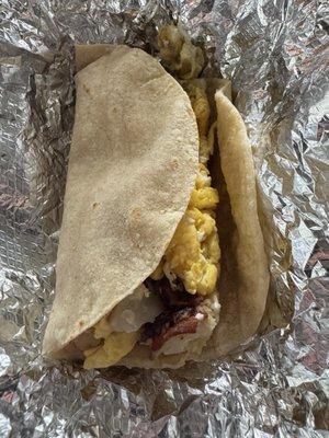 Bacon, potato, and egg taco on a corn tortilla.