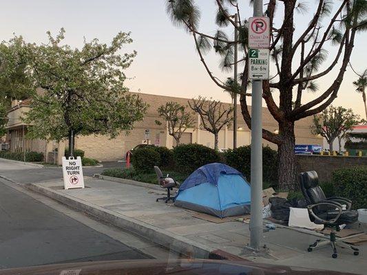 There's a unhoused or homeless person at the entrance with office chairs.